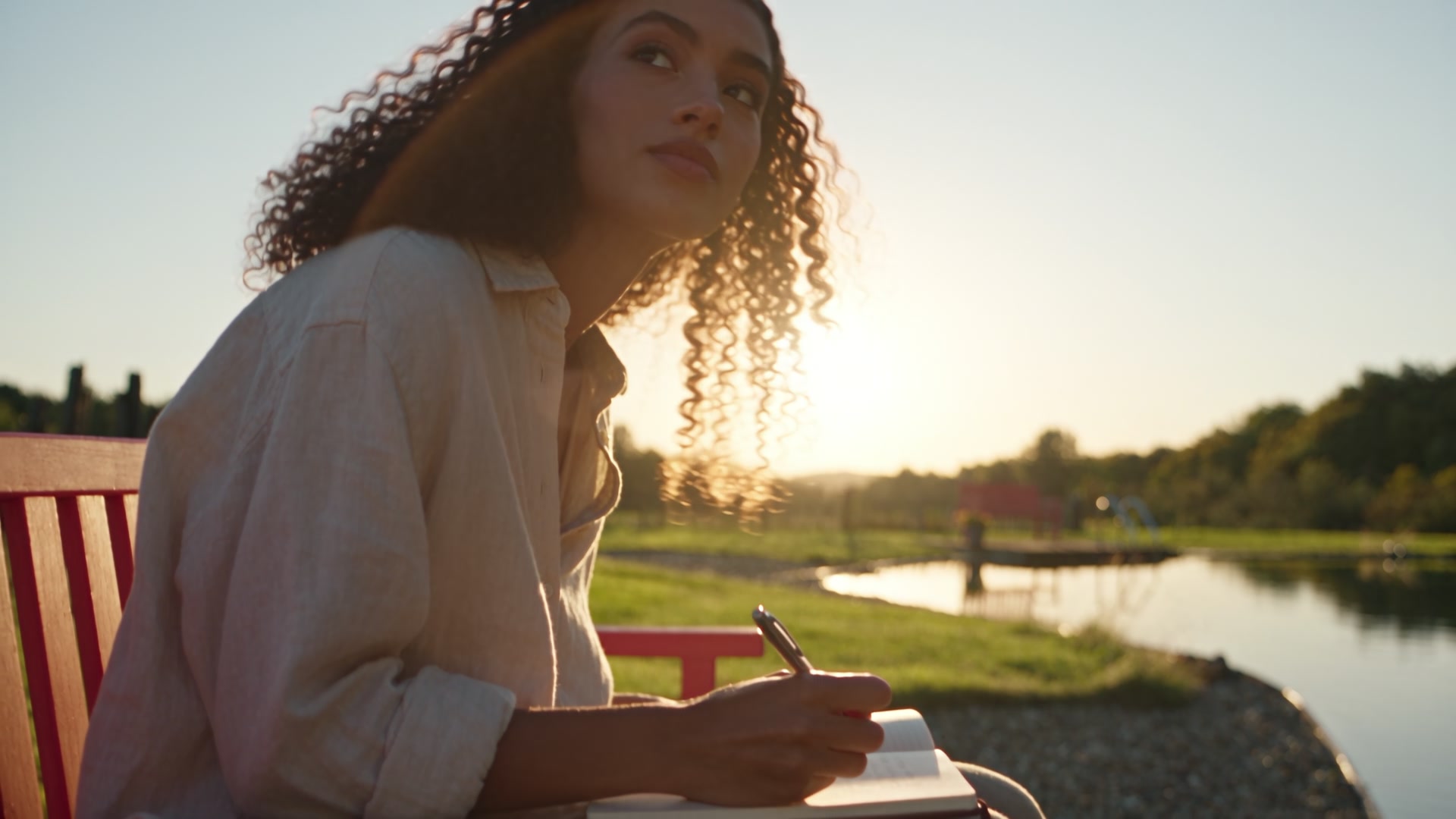 A guest looking back over her shoulder by the pond at sunset