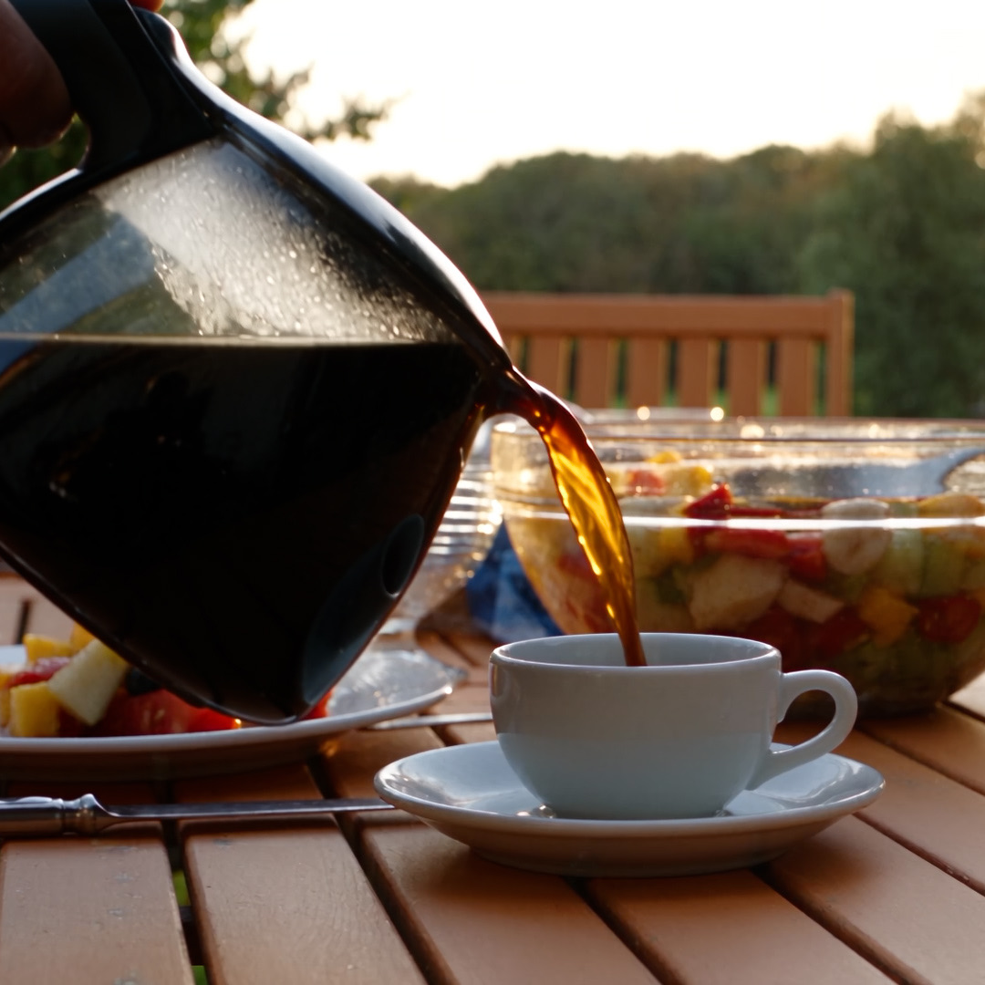 Coffee poured at a breakfast table outdoors, then a guest sipping it