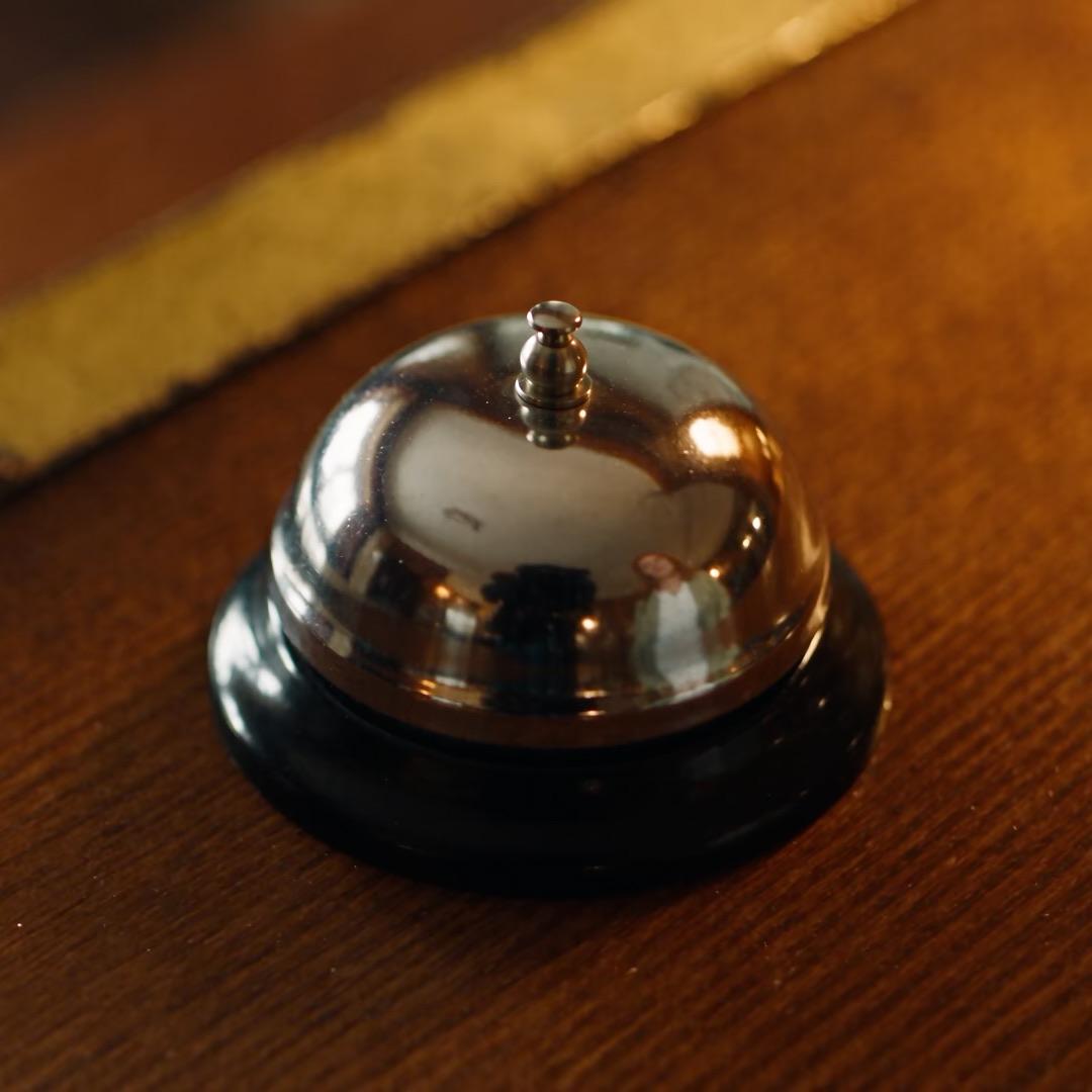 A guest rings the bell at a hotel reception and smiles